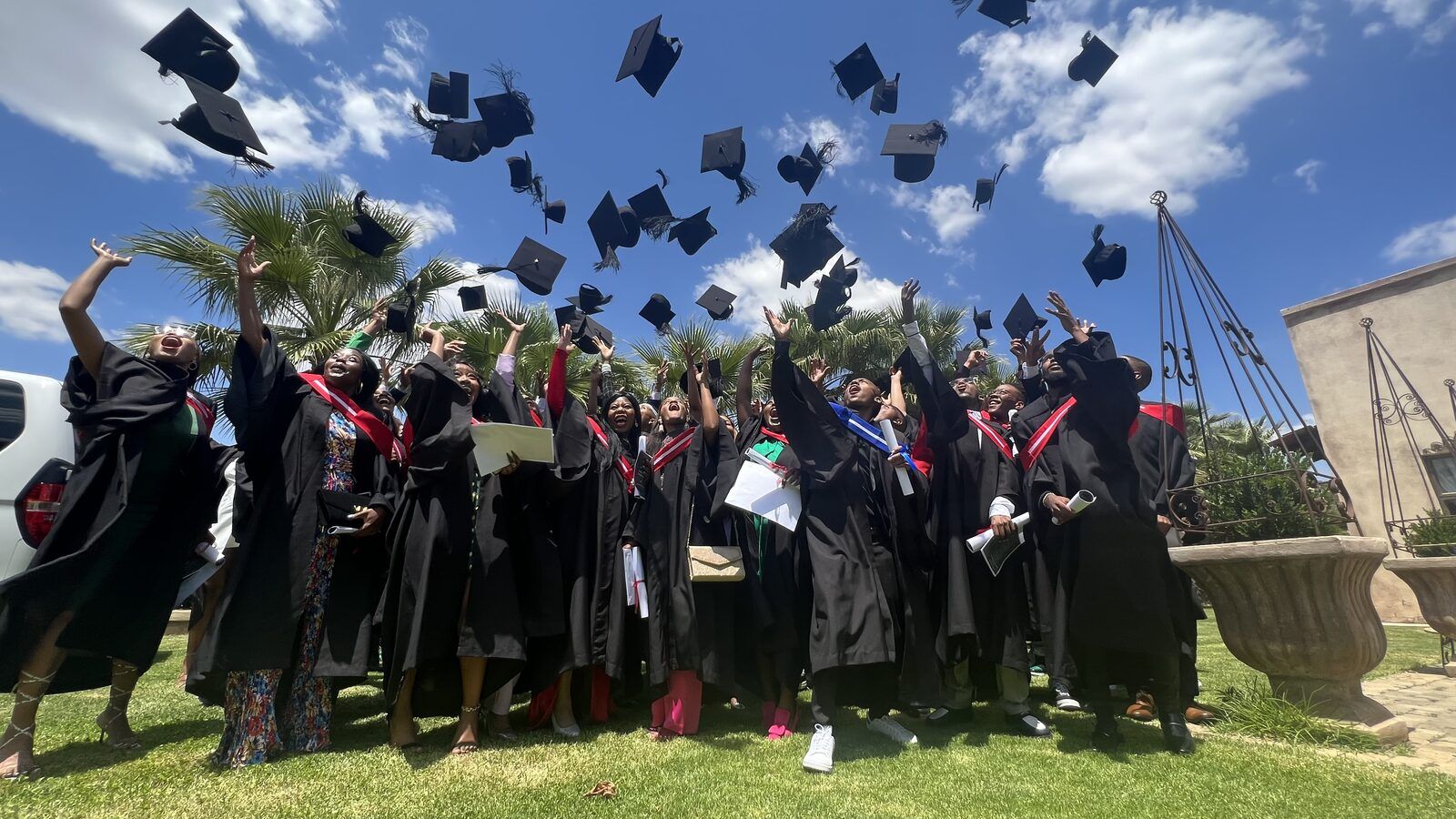 PASMA graduates throwing their caps in the air on graduation day