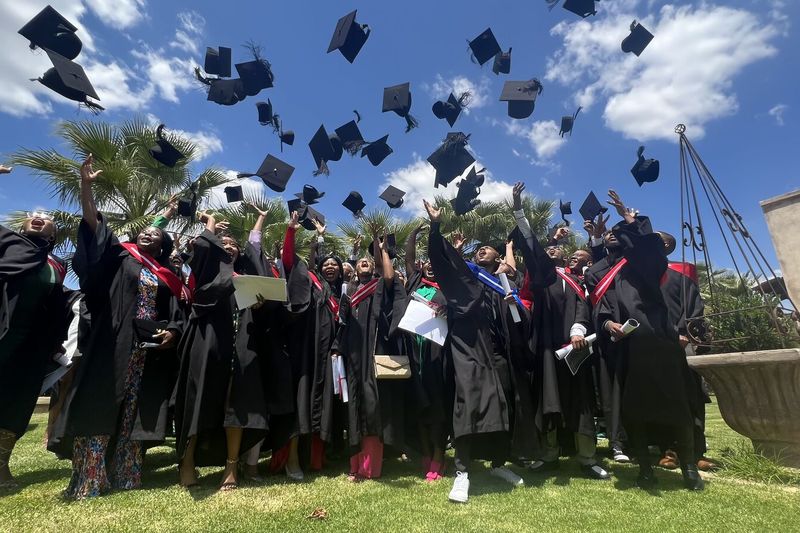 PASMA graduates throwing their caps in the air on graduation day