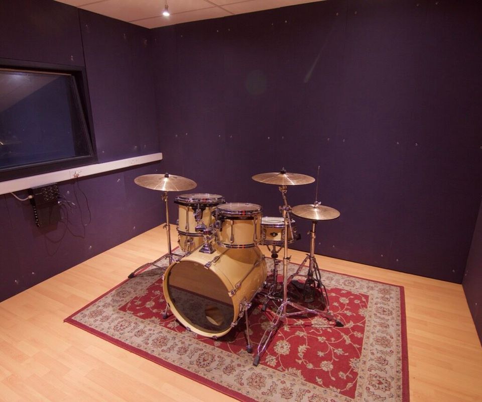 The drum tracking room at PASMA, kit mic'd up under warm practical lights