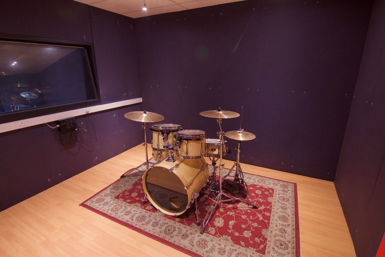 The drum tracking room at PASMA, kit mic'd up under warm practical lights
