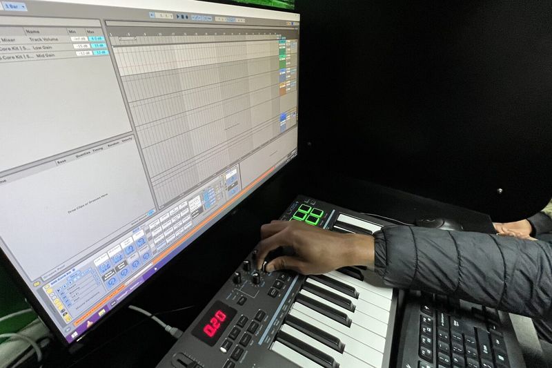 A student programming beats on a MIDI keyboard in the green production lab